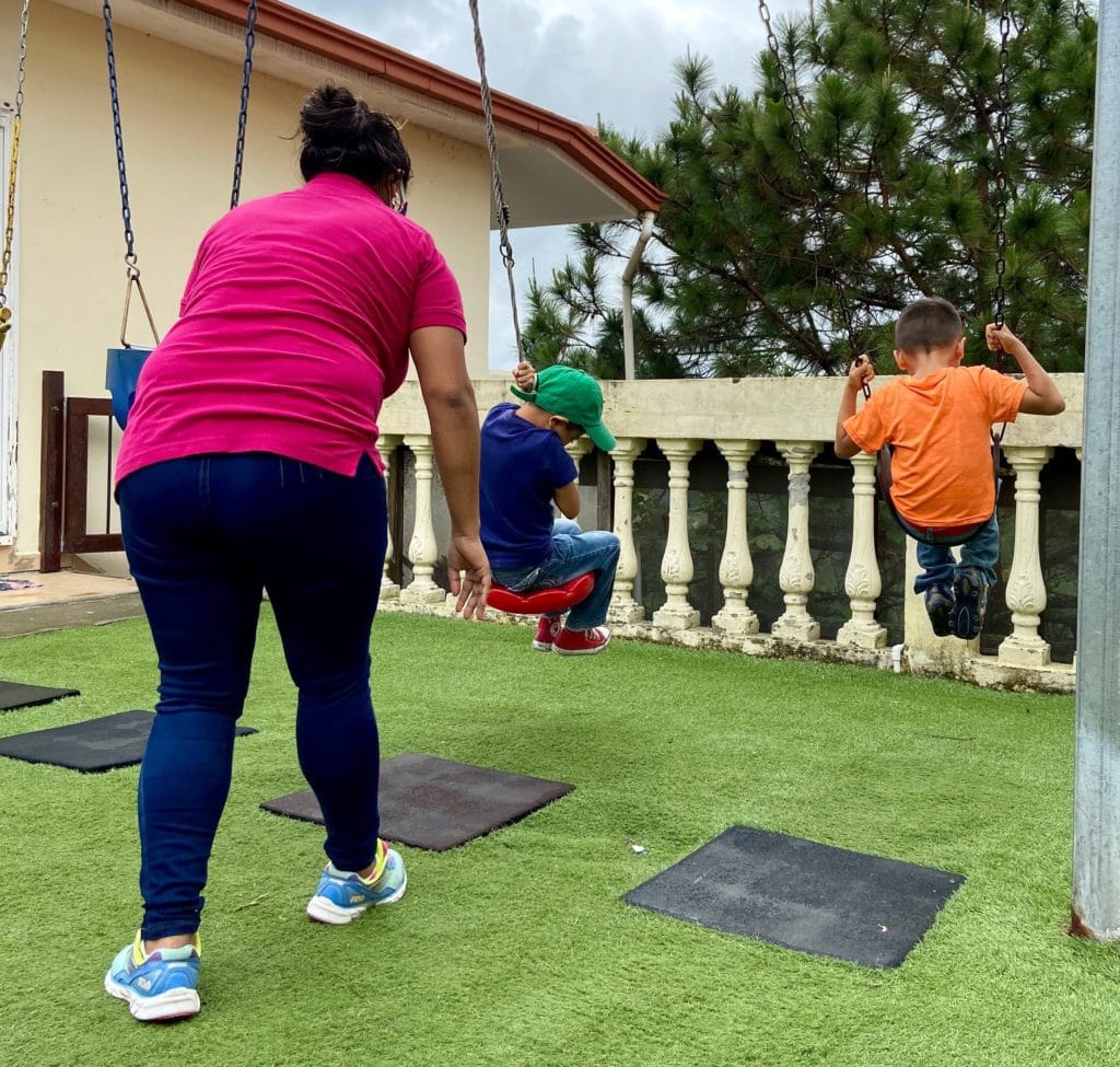 boys with caregiver on swings